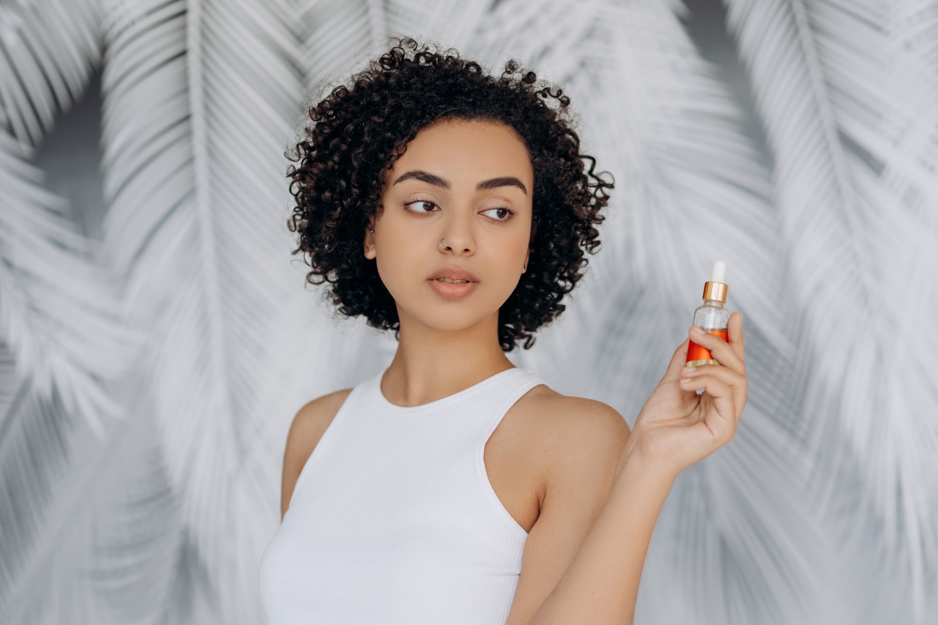 Woman in White Tank Top Holding A Bottle Of Essential Oil
