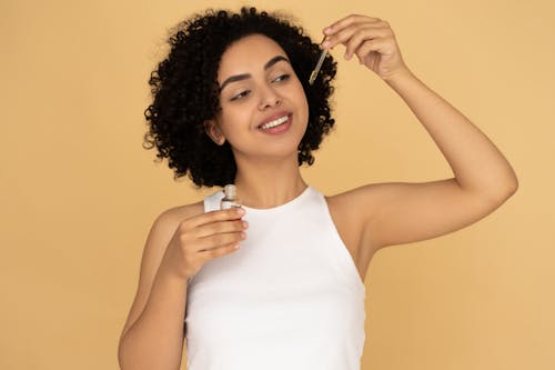 Free Woman in White Tank Top Holding A Bottle Stock Photo