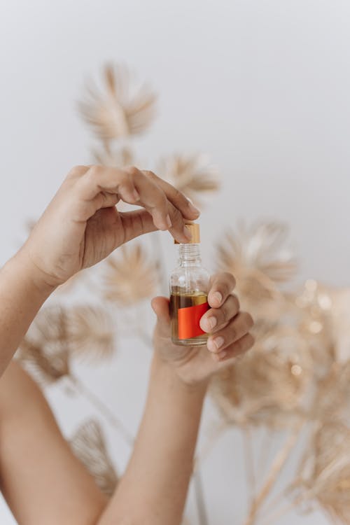 Person Holding Clear Glass Bottle With Red Liquid