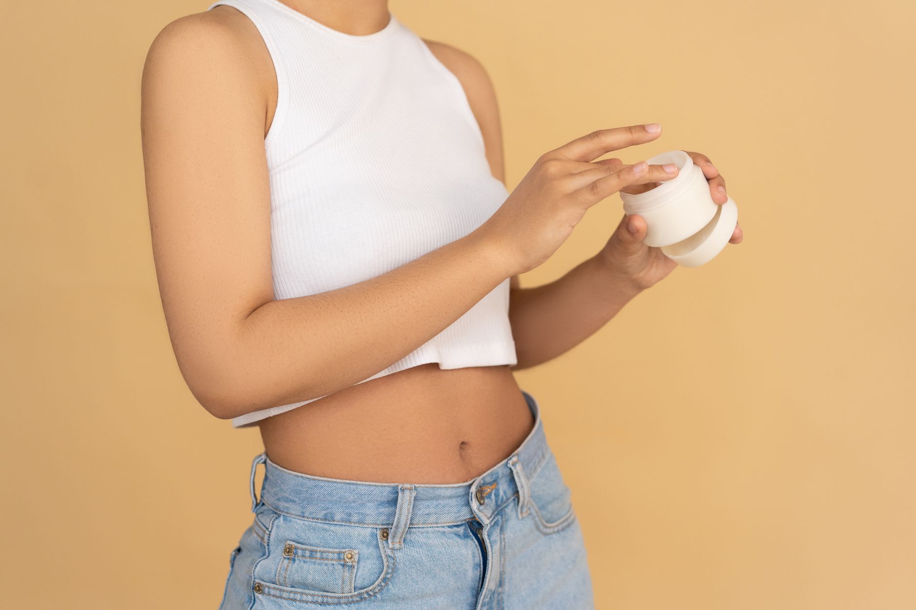 Woman in White Tank Top and Blue Denim Jeans Holding White Ceramic Mug