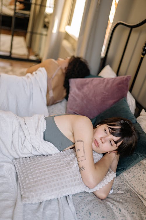 A Woman in a Gray Tank Top Lying Down on the Bed