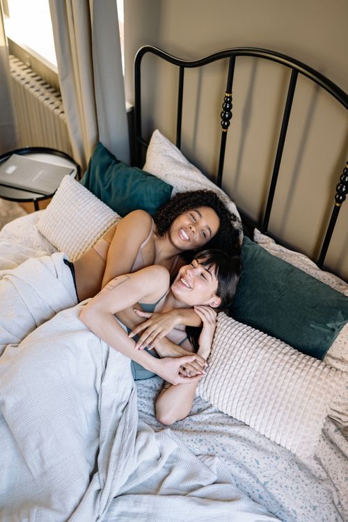 Free A joyful lesbian couple embracing sweetly in a cozy bedroom setting, expressing love and connection. Stock Photo