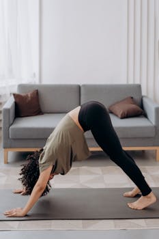 A young woman performing yoga pose in a modern living room setting, promoting health and relaxation.