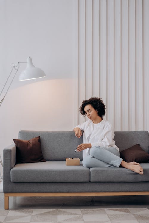Free Woman in White Dress Shirt Sitting on Couch Stock Photo