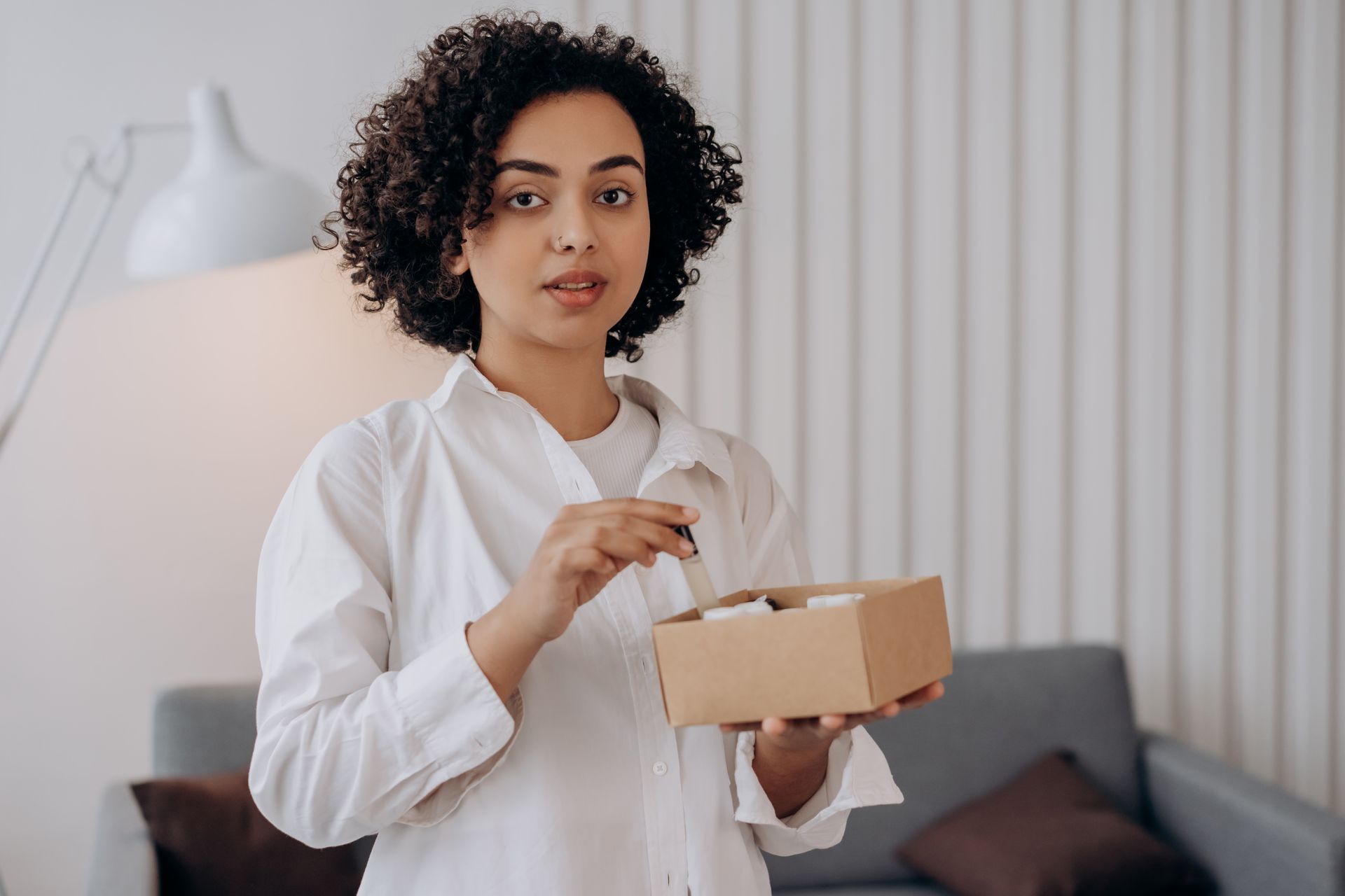 Woman in White Long Sleeve Shirt Holding A Box Of Essential Oils