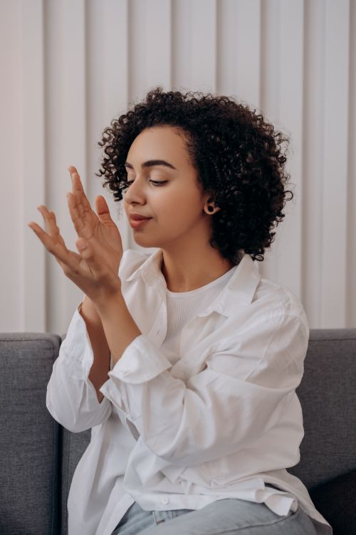 Free A woman with curly hair enjoys aromatherapy in a modern indoor setting, promoting relaxation and wellness. Stock Photo