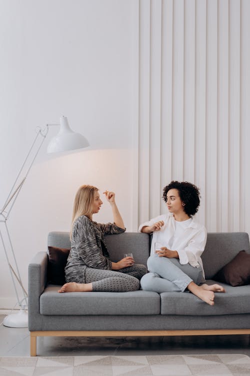 Free Two Women Sitting on Gray Couch Relaxing Stock Photo