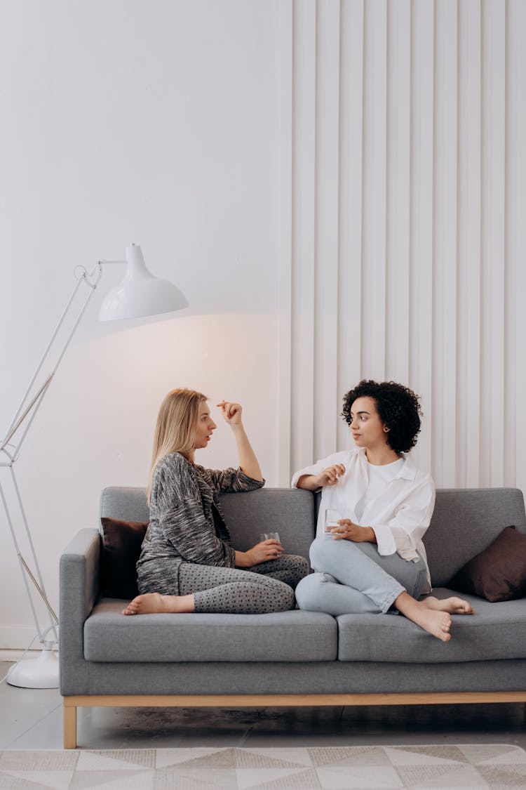 Two Women Sitting On Gray Couch Relaxing