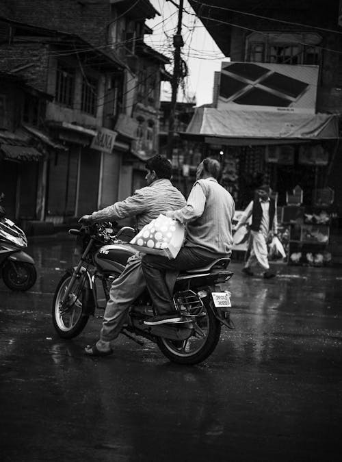 Grayscale Photo of Two Men Riding a Motorcycle