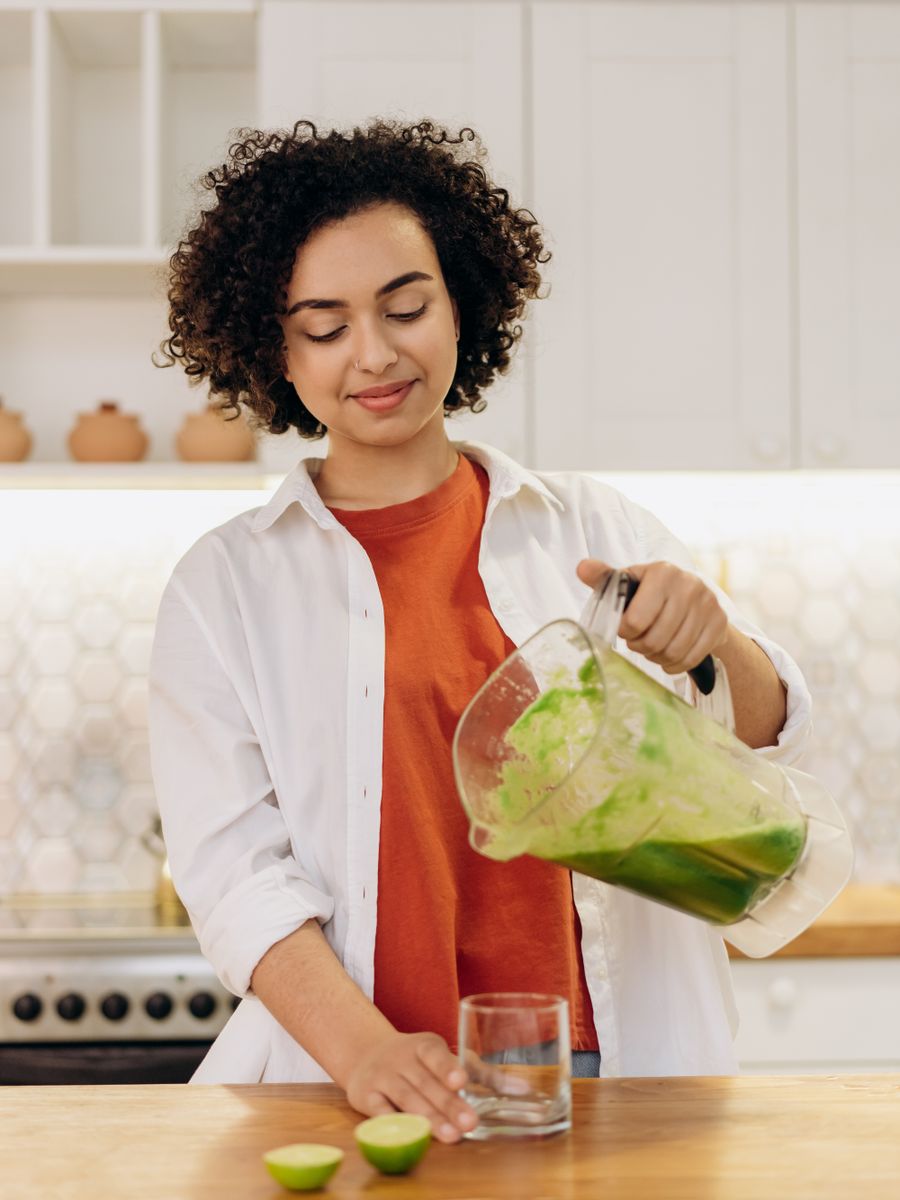 Woman pouring a fresh smoothie into a glass