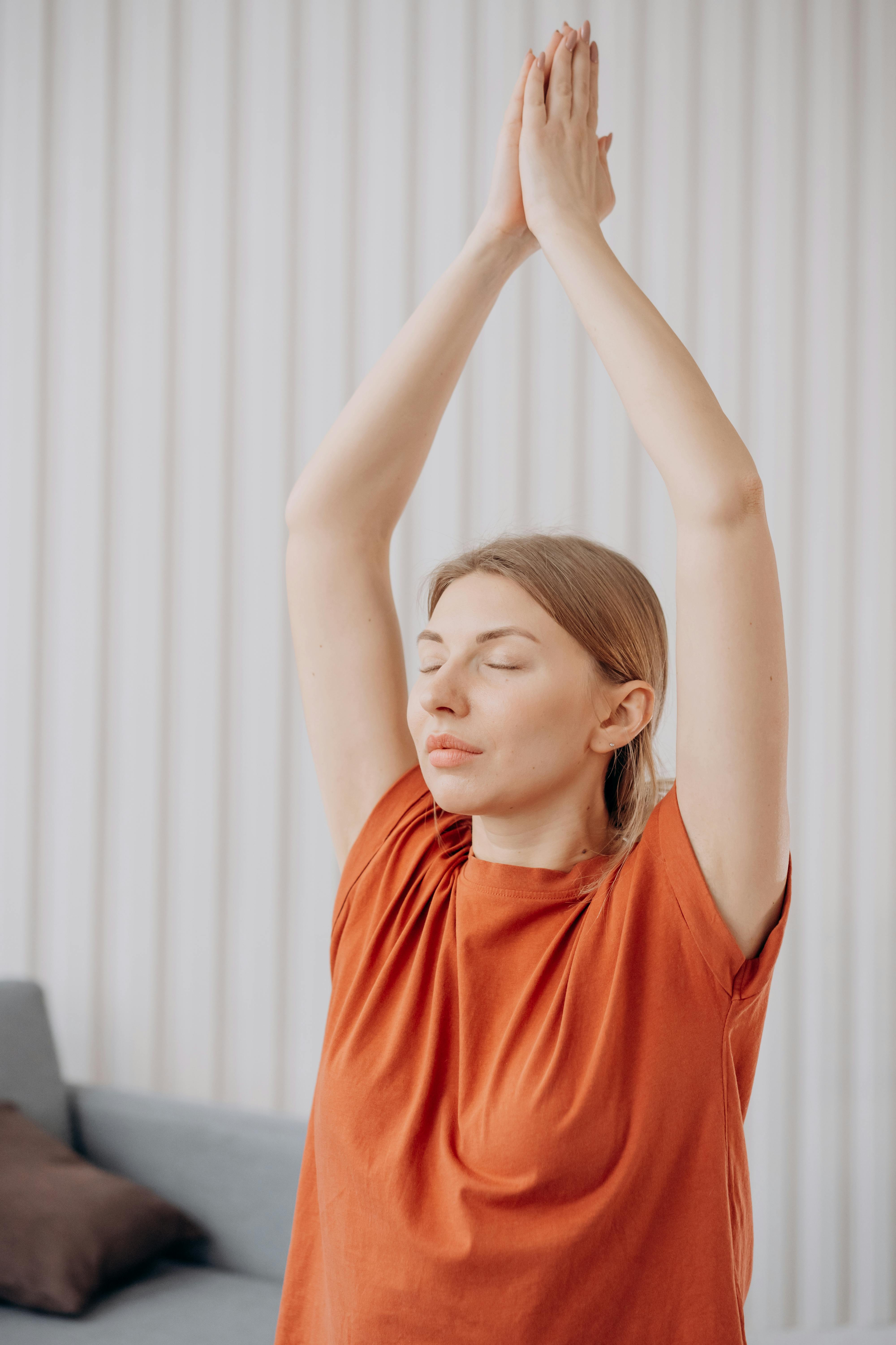 woman in orange crew neck t shirt raising her hands