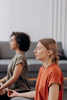 Two women practicing mindfulness meditation indoors, promoting inner peace and wellbeing.