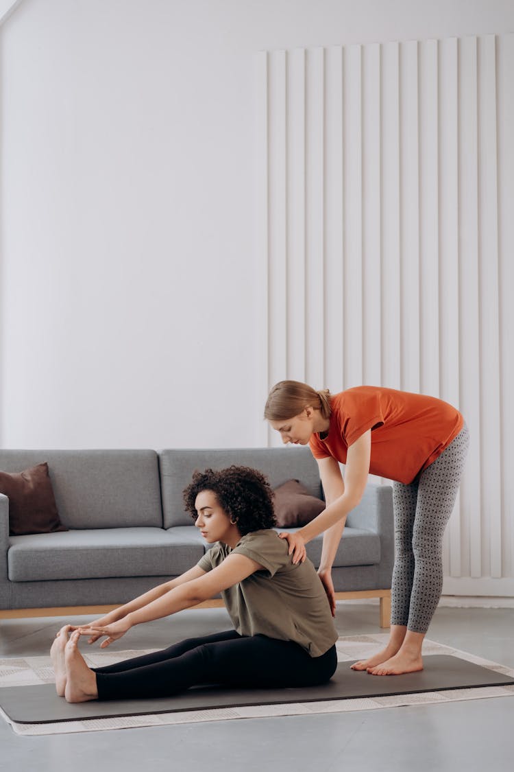 Two Women Helping Each Other Doing Yoga