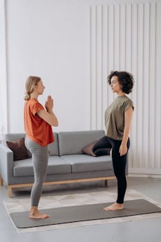 Two women engaged in a yoga session at home, focusing on balance and mindfulness.