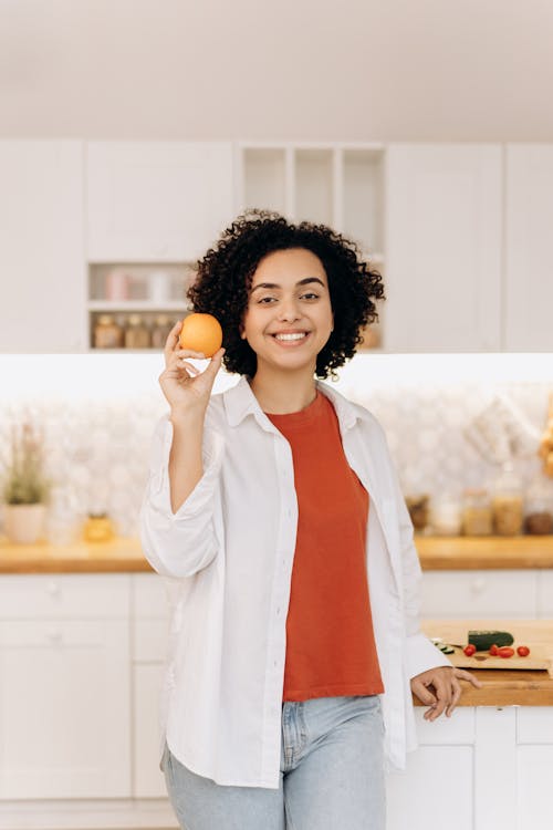 Woman in White Blazer Holding Orange Fruit