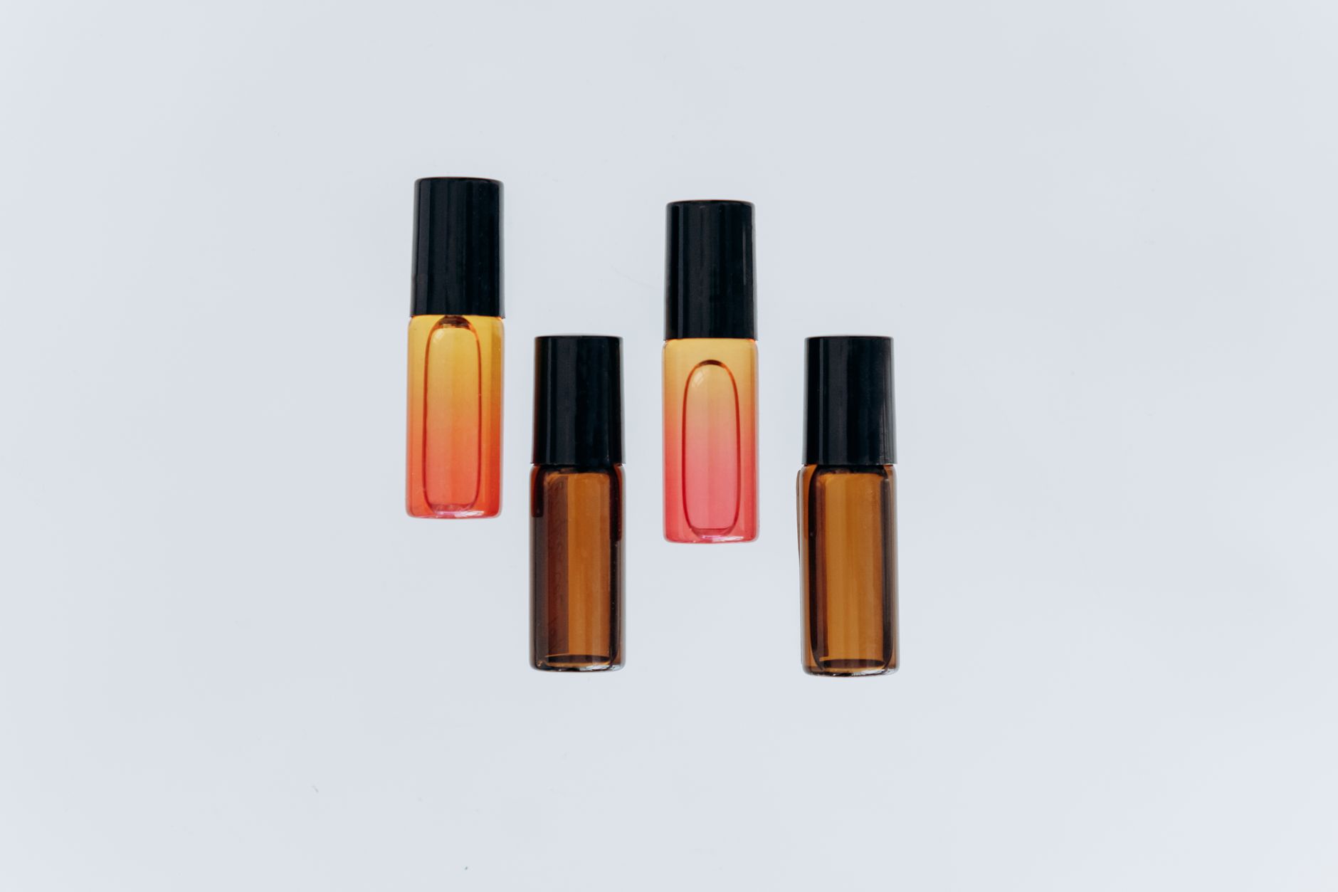 High-angle view of assorted roller bottles used for essential oils with a clean white background.
