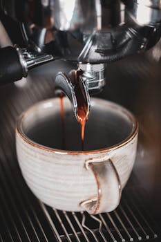 A detailed shot of espresso pouring into a ceramic cup from a coffee machine. Perfect for breakfast and coffee themes.