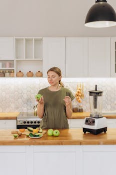 A woman prepares a green apple smoothie in a modern kitchen setting.