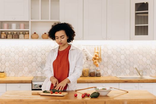 A woman slicing vegetables in a modern kitchen, showcasing healthy cooking and lifestyle.