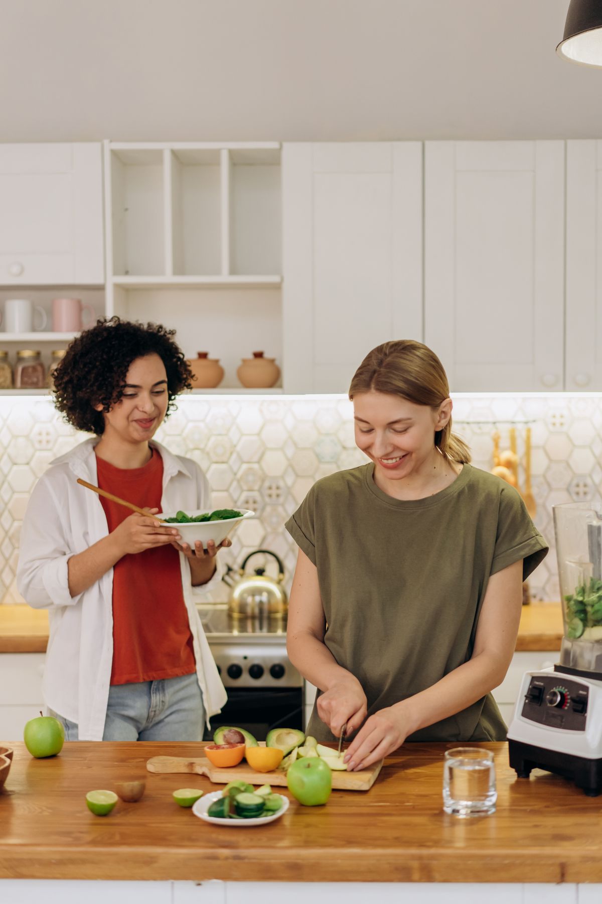 Two women cooking together in a bright kitchen while splitting holiday prep jobs
