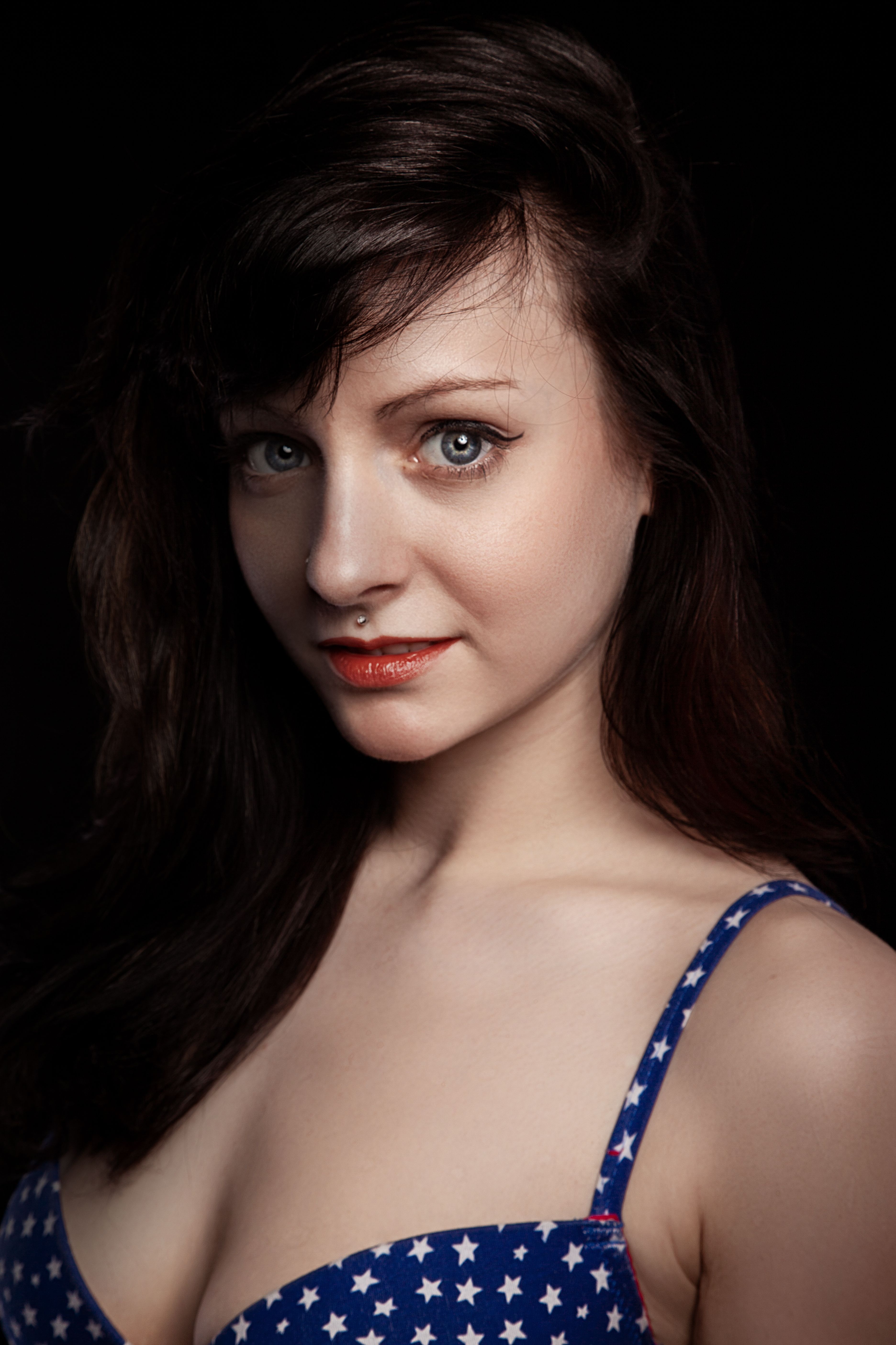 Studio portrait of a brunette woman wearing a star-patterned dress, showcasing elegance and beauty.