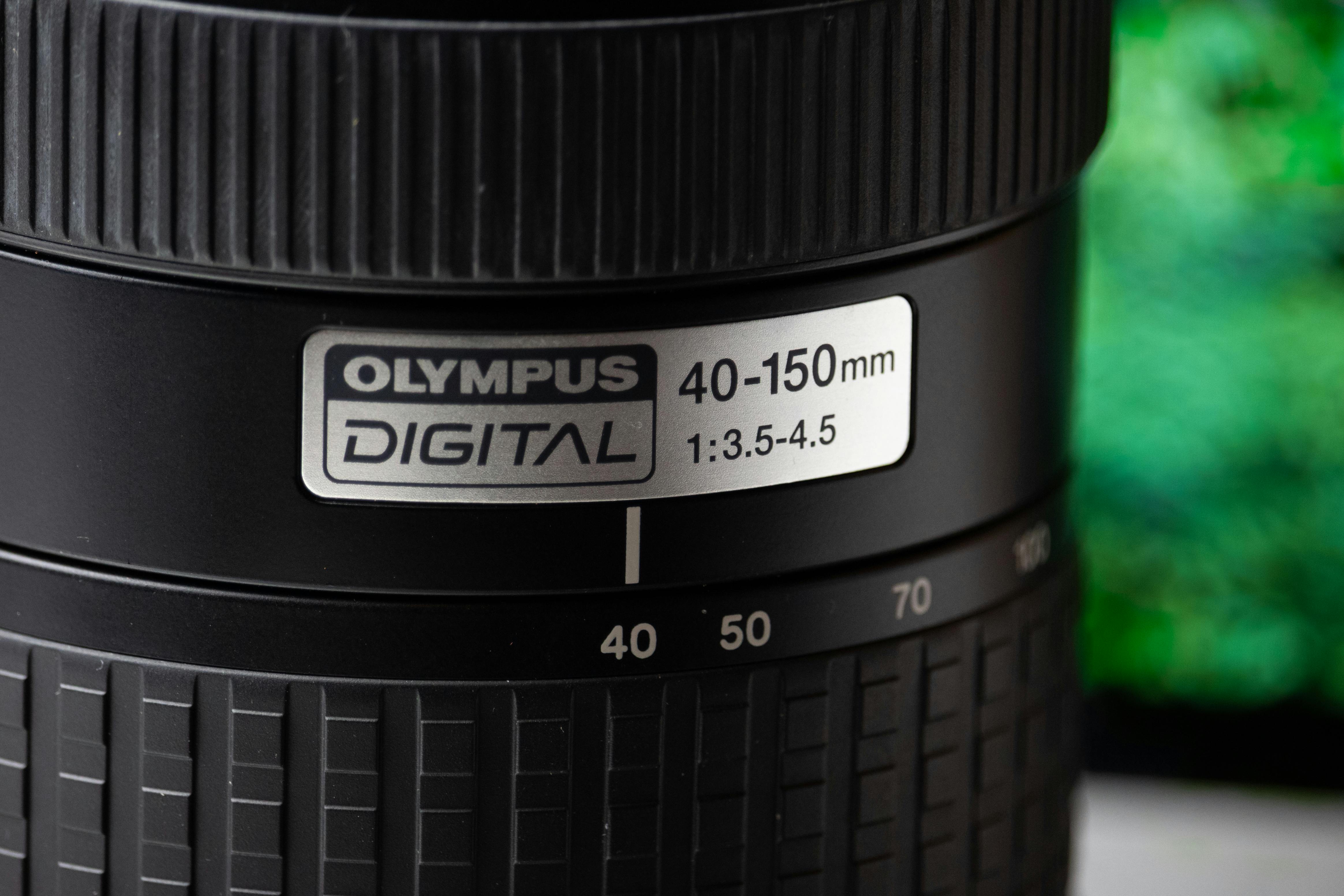 Detailed close-up of an Olympus digital camera lens showing aperture settings and design.