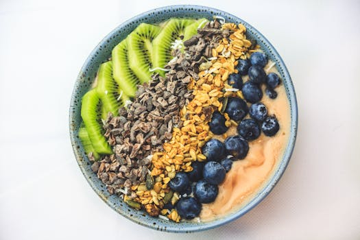 Healthy vegan smoothie bowl featuring kiwi, blueberries, cacao nibs, granola, and seeds.