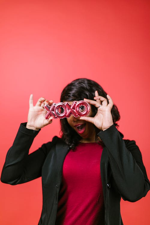 Woman in Black Blazer Holding a Xoxo Balloon Letters