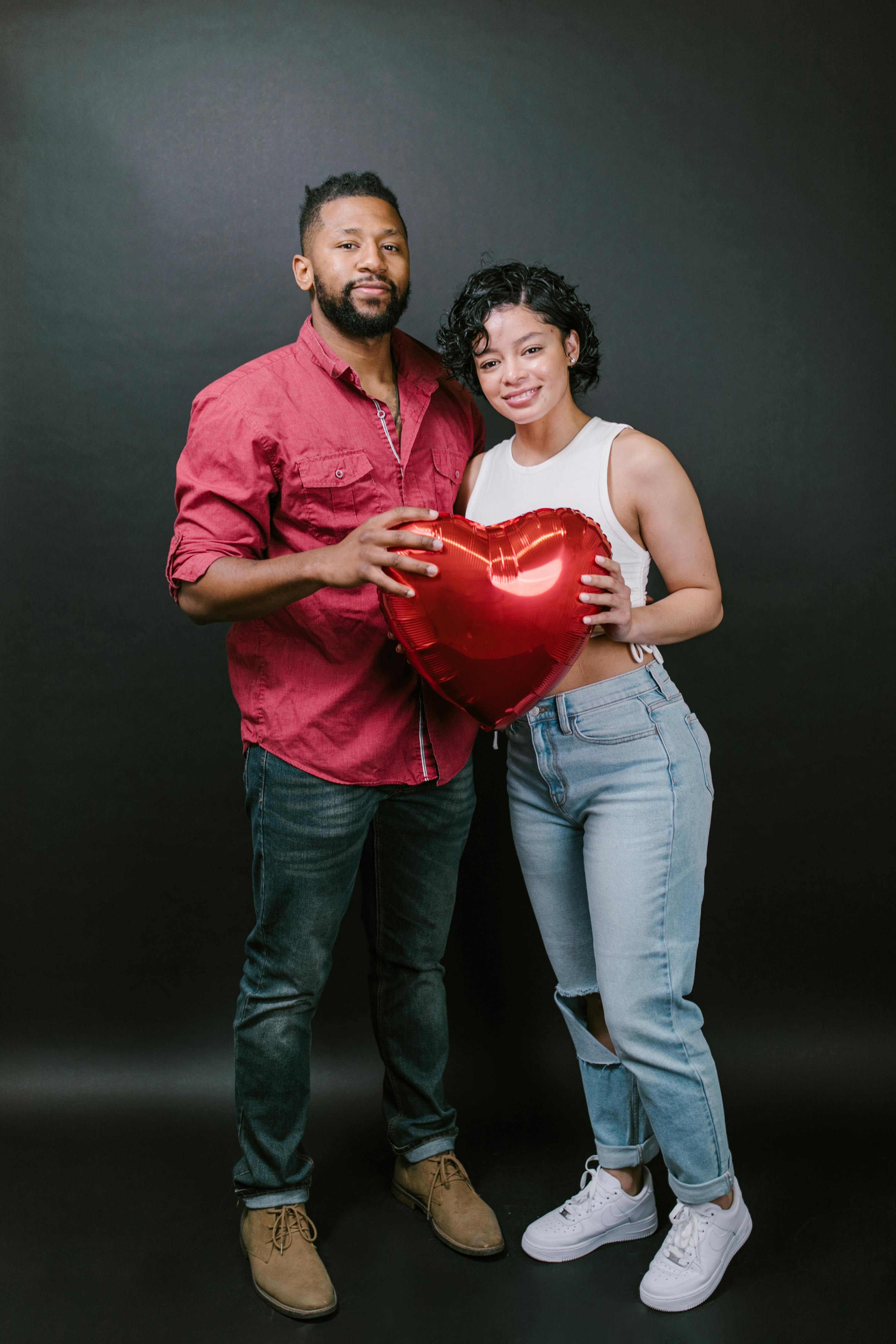 couple holding a red heart shaped balloon