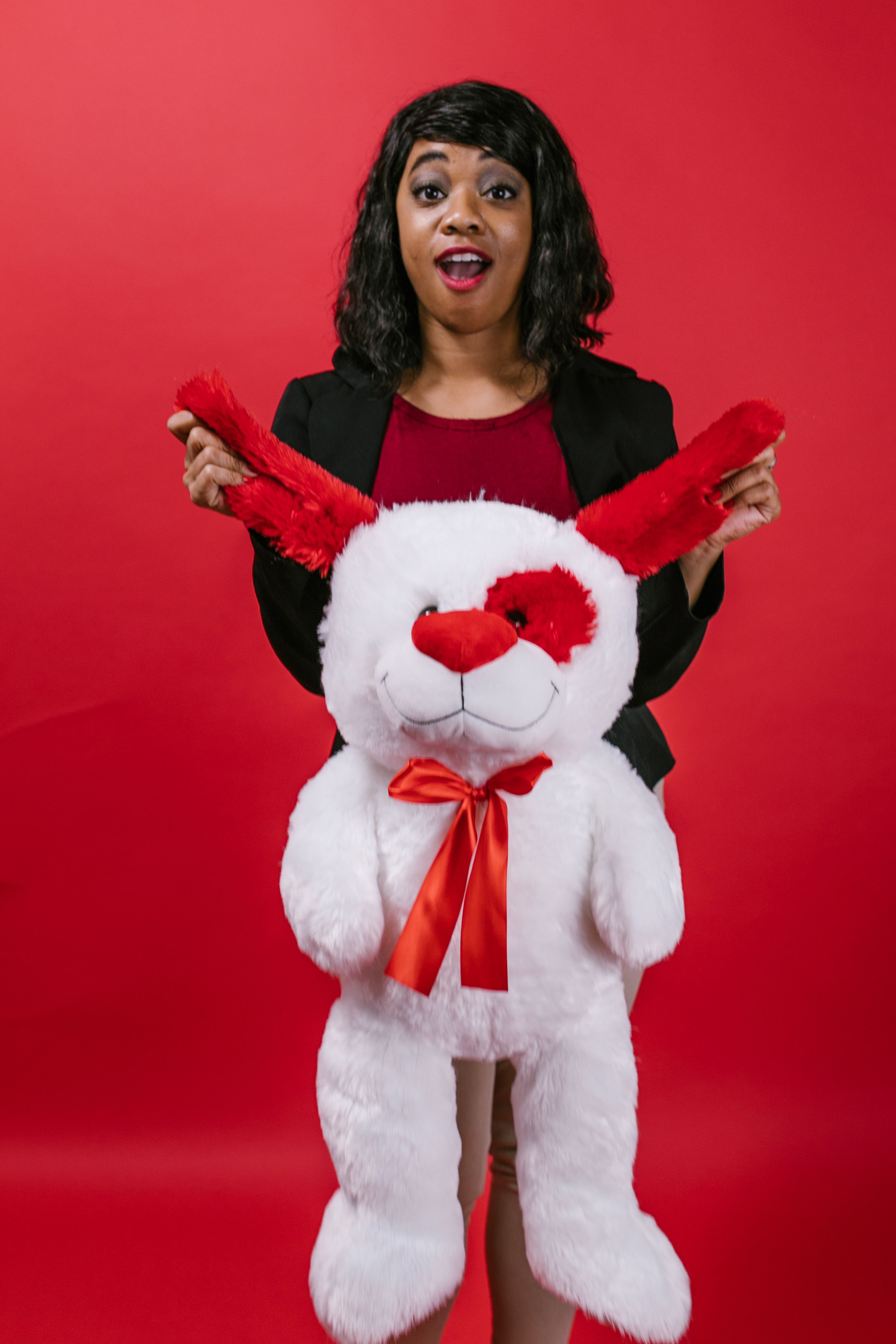 A happy woman holding a plush toy perfect for Valentine's Day gifting.