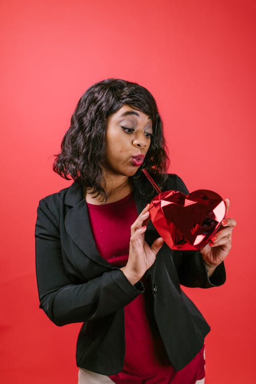 Woman Holding a Red Heart Shaped Ornament