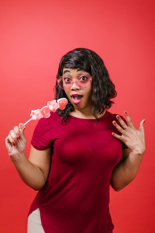 Free Woman Looking Surprised While Holding a Lollipop Stock Photo