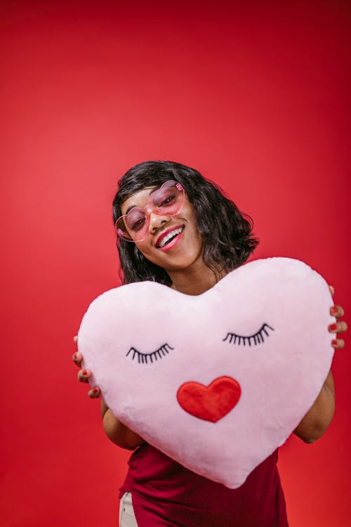 Woman Smiling While Holding Pink Heart Pillow