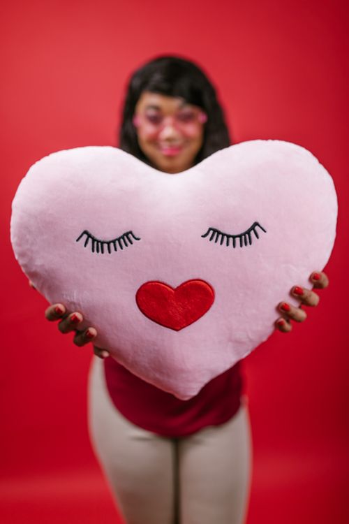 Free A person holding a heart-shaped pillow with a red heart design, ideal for Valentine’s Day gift ideas. Stock Photo
