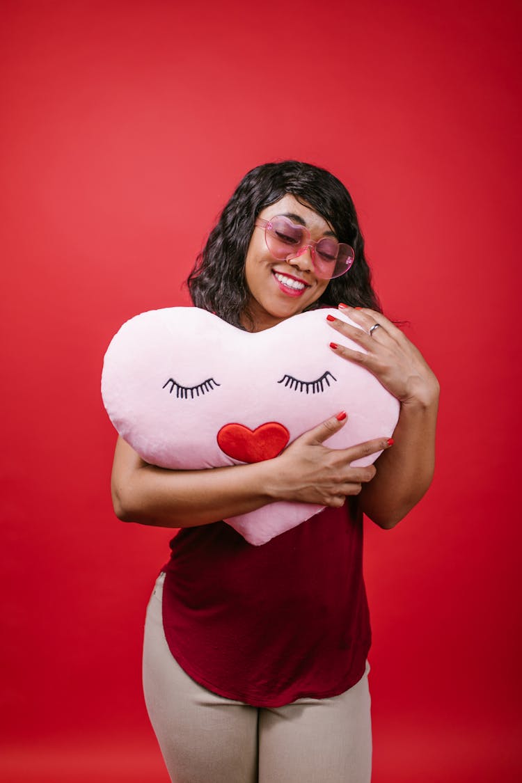 Woman In Red Crew Neck Shirt Holding A Pink Heart Shaped Pillow