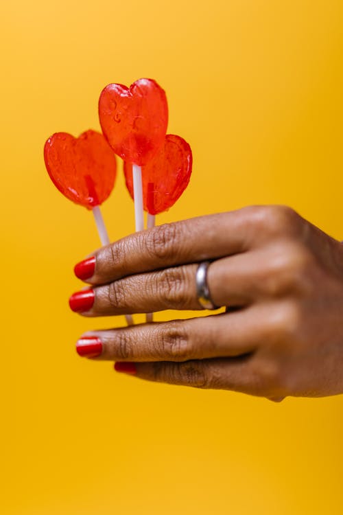 Person Holding Red Heart Shaped Lollipops