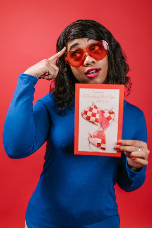Free Woman in heart sunglasses holding a Valentine's card with a red background. Stock Photo
