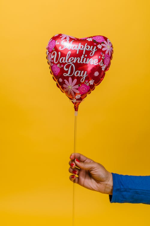 Free Person Holding a Red Heart Shaped Balloon Stock Photo