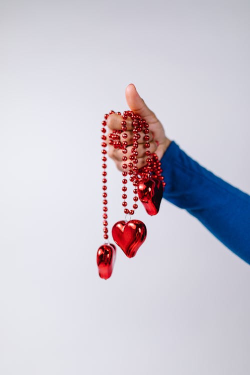 Person Holding Red Beaded Necklaces