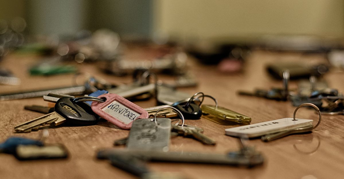 Macro shot of various metallic keys scattered on a wooden surface.