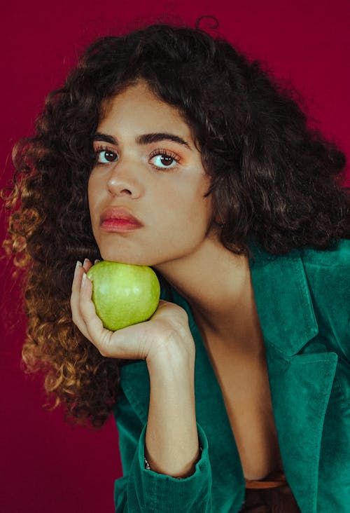 Pretty Woman Looking at Camera while Holding a Green Apple