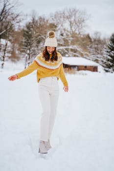 A young woman in a yellow sweater walks joyfully in the snow.