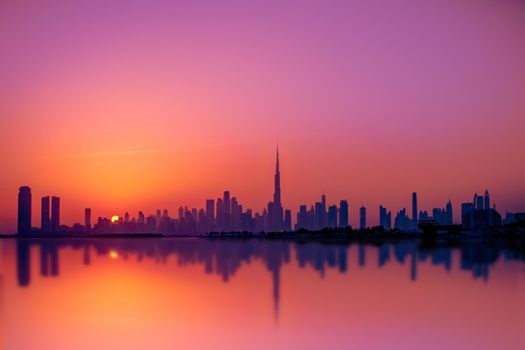 Stunning view of Dubai cityscape at sunset, featuring Burj Khalifa reflecting on the waterfront.