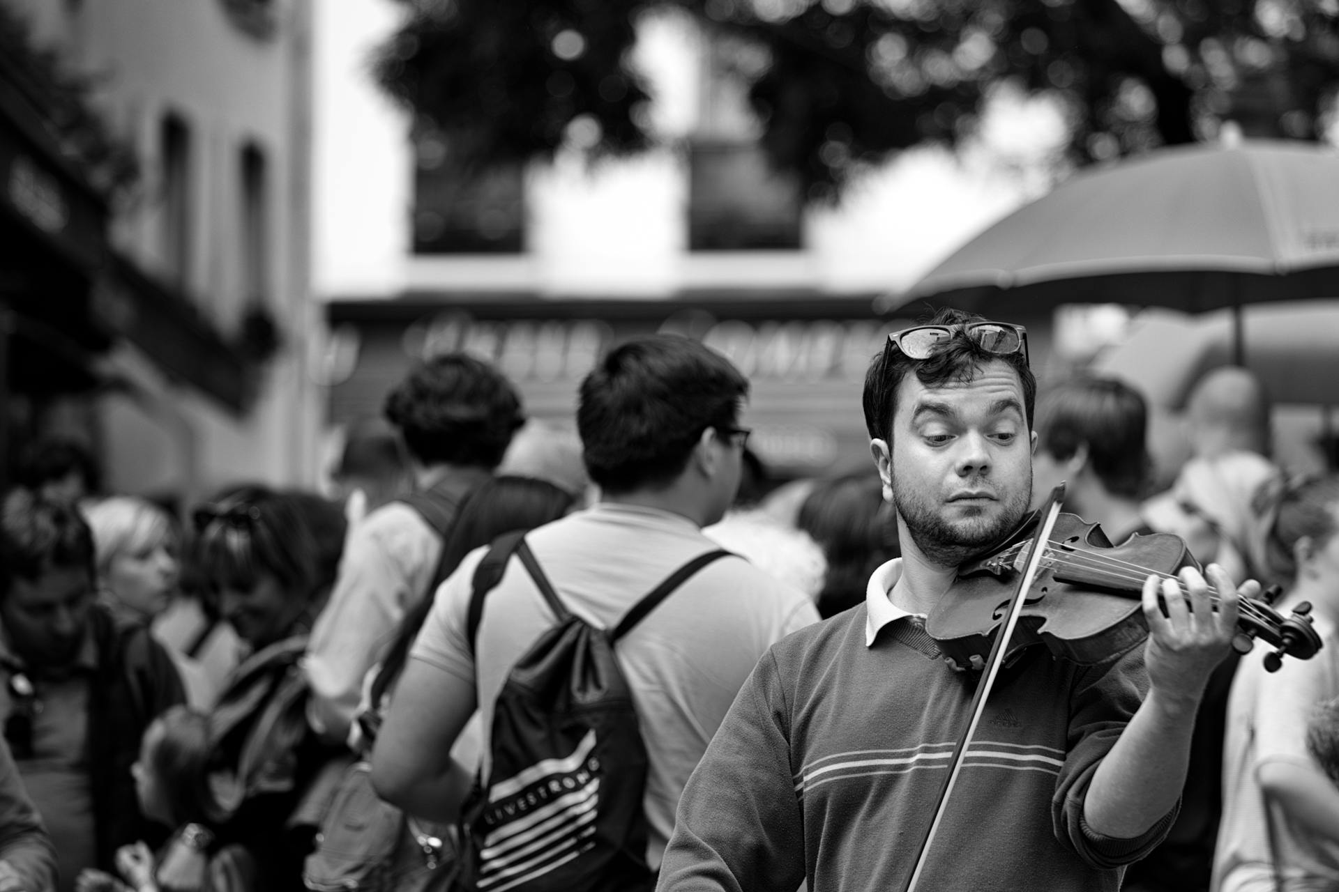 A street musician passionately plays the violin amidst a crowd in Paris, capturing the city's vibrant atmosphere.