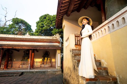 Free Full body side view of Asian female in headdress standing on stairs of weathered building in oriental style in town Stock Photo