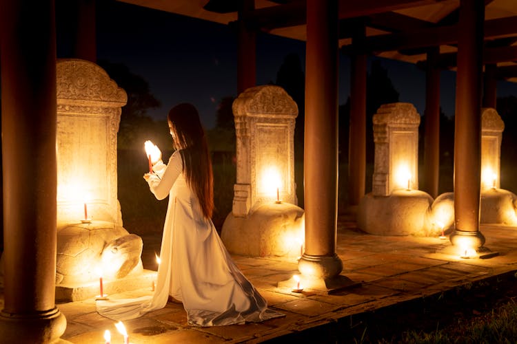 Unrecognizable Woman With Candle Praying Near Stele