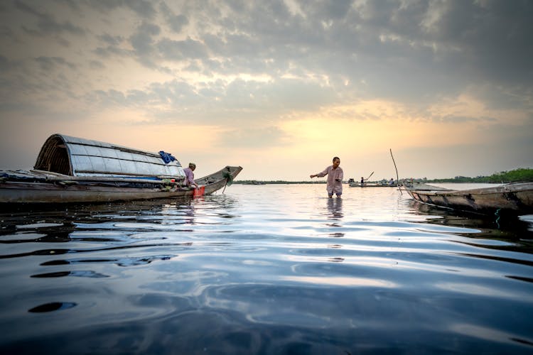 People With Fishing Tools In Boat On River