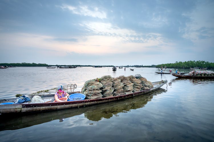 Woman In Boat With Fishing Equipment On River