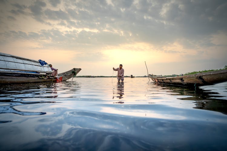 People With Fishing Tools In Boat On River