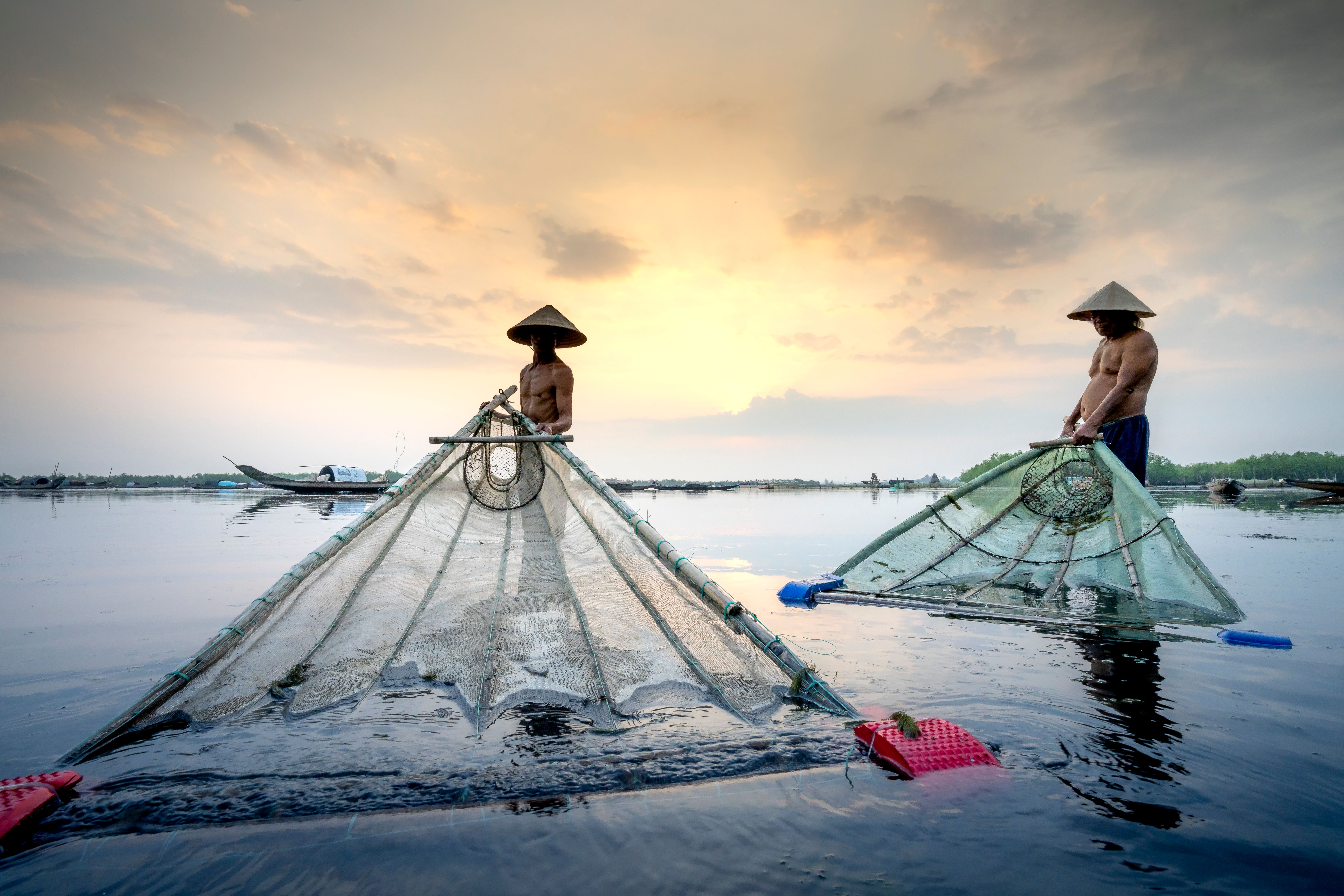 Fishermen in Vietnamese hats in water 